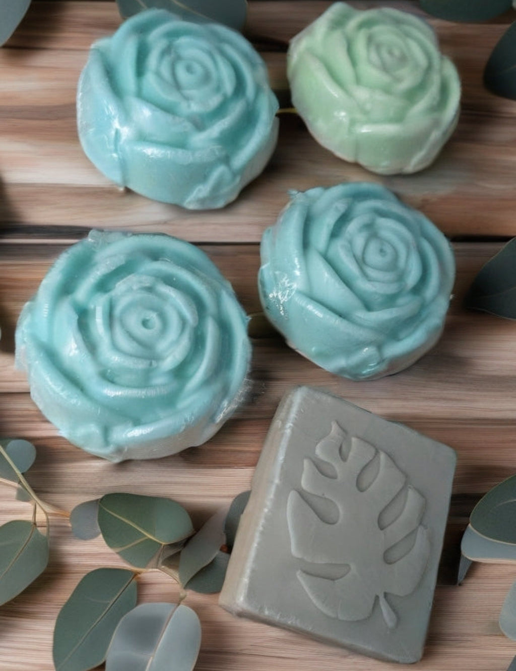 Green soap bars with leaf patterns on a wooden surface with eucalyptus leaves.