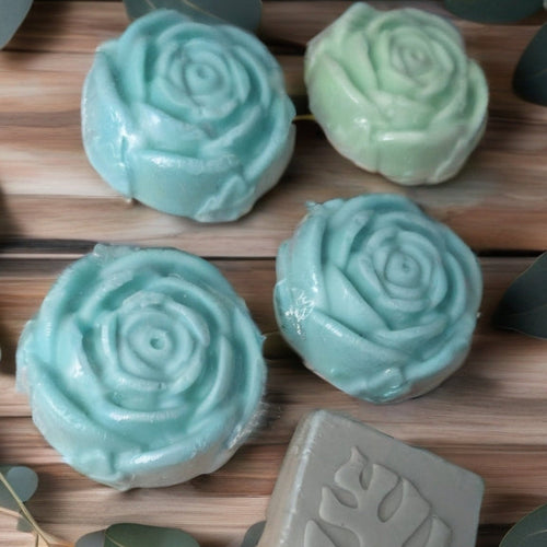 Green soap bars with leaf patterns on a wooden surface with eucalyptus leaves.